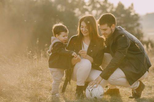 A cheerful family bonding outdoors with a soccer ball, enjoying a sunny day in the grass.