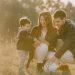 A cheerful family bonding outdoors with a soccer ball, enjoying a sunny day in the grass.
